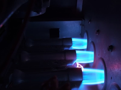 Bright blue flames ignite inside a furnace burner, illustrating proper heating system operation.