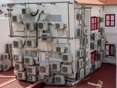A building wall densely covered with numerous outdoor air conditioning units