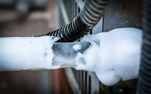 A metal pipe is thickly covered in white ice and frost