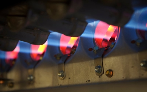 A close-up shows the interior of an operating gas furnace with multiple burners ignited